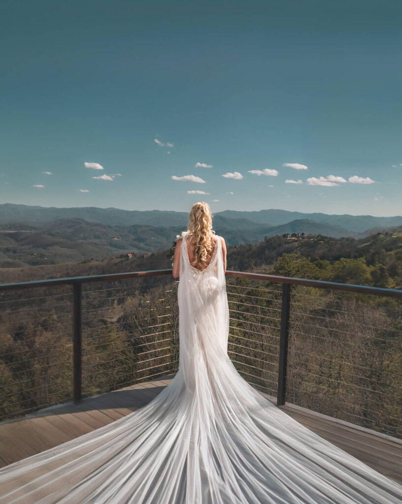 Bride in a flowing wedding gown overlooking the Smoky Mountains at a luxury destination wedding venue